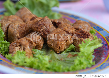 Crispy fried tofu rolls served with fresh lettuce on decorative plate featuring savory texture and traditional Asian style snack presentation Crispy fried tofu rolls served with fresh lettuce on decorative plate featuring savory texture and traditional Asian style snack presentation 139632976