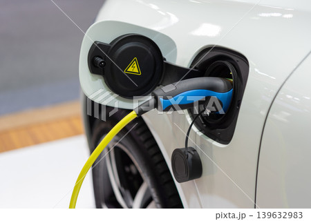 Closeup of electric car charging port with plugged cable highlighting sustainable transportation clean energy technology and modern mobility infrastructure Closeup of electric car charging port with plugged cable highlighting sustainable transportation clean energy technology and modern mobility infrastructure 139632983