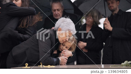 Funeral, crying family and child hug grandmother for support, mourning depression and death at emotional burial event. Dead, love and kid hugging senior woman, grandma and grief at farewell ceremony Funeral, crying family and child hug grandmother for support, mourning depression and death at emotional burial event. Dead, love and kid hugging senior woman, grandma and grief at farewell ceremony 139634805