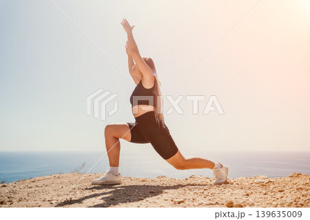 Woman lunge exercise performed on a rocky clifftop overlooking the sea during a sunny outdoor morning fitness workout Woman lunge exercise performed on a rocky clifftop overlooking the sea during a sunny outdoor morning fitness workout 139635009