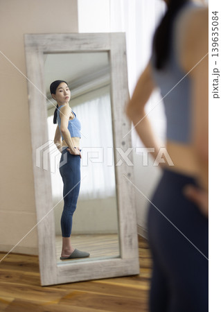 鏡で体型をチェックするヨガウェアを着た日本人のミドル女性 鏡で体型をチェックするヨガウェアを着た日本人のミドル女性 139635084