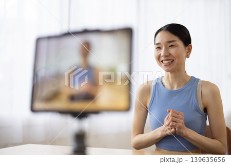 タブレットの前で話すヨガウェアを着た日本人のミドル女性 139635656