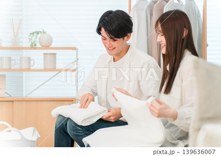 リビングで洗濯物を畳む笑顔の夫婦,カップル（家事参加,家事分担） 139636007