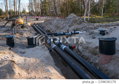 Insulated underground utility pipes installed in trench for district heating construction project Insulated underground utility pipes installed in trench for district heating construction project 139636170