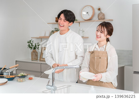マイホームのキッチンで一緒に家事・お皿洗いををしながら会話する仲良しのアジア人夫婦の男女 マイホームのキッチンで一緒に家事・お皿洗いををしながら会話する仲良しのアジア人夫婦の男女 139636225