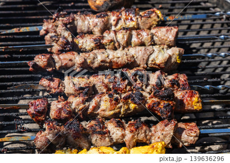 Juicy lamb skewers roasting on outdoor barbecue grill. Juicy lamb skewers roasting on outdoor barbecue grill. 139636296