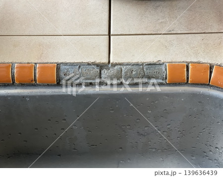 Missing Orange Tiles And Exposed Cement Mortar Near Stainless Steel Kitchen Sink Missing Orange Tiles And Exposed Cement Mortar Near Stainless Steel Kitchen Sink 139636439