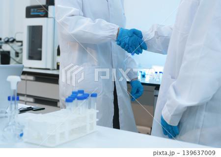 Scientists Shaking Hands in Laboratory Representing Teamwork, Success, and Medical Research Collaboration. 139637009