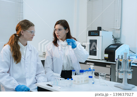 Scientist analyzing and dropping a sample into a glassware. 139637027