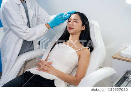 Asian woman consulting with a doctor at a modern aesthetic clinic for facial treatment. 139637080