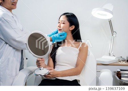 Asian woman consulting with a doctor at a modern aesthetic clinic for facial treatment. 139637109
