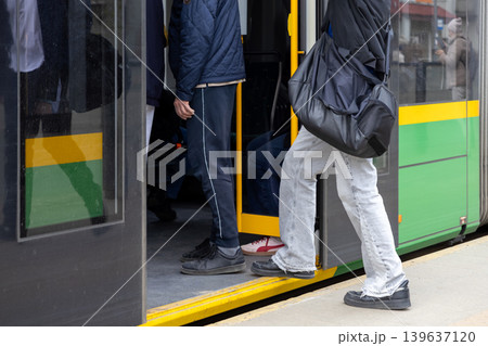 Passengers boarding a modern public tram at a city stop, showcasing daily urban commute, mass transport efficiency, and active city lifestyle during the busy morning rush hour travel period Passengers boarding a modern public tram at a city stop, showcasing daily urban commute, mass transport efficiency, and active city lifestyle during the busy morning rush hour travel period 139637120