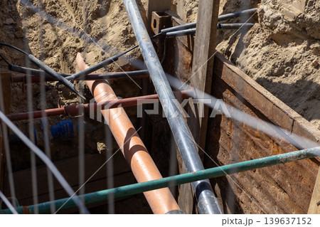 Industrial water pipe burst causing high pressure leak in an open construction trench, creating a hazardous site condition that requires immediate repair and maintenance by engineering crews 139637152
