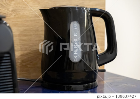 Black electric kettle on kitchen counter, featuring a clear water level indicator for convenient boiling, representing modern home appliance and daily beverage preparation routine Black electric kettle on kitchen counter, featuring a clear water level indicator for convenient boiling, representing modern home appliance and daily beverage preparation routine 139637427