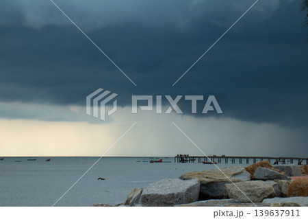 Storm cloud seascape rocky shore calm water pier horizon dark sky rain shower cloudy sky coastal landscape 139637911