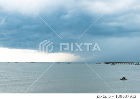 Storm cloud over calm sea, distant boat and pier on horizon 139637912