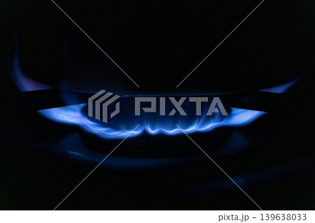 A bright blue gas flame burns on a modern stove burner in the dark, illustrating efficient heating, energy consumption, and essential cooking preparation for a daily kitchen life A bright blue gas flame burns on a modern stove burner in the dark, illustrating efficient heating, energy consumption, and essential cooking preparation for a daily kitchen life 139638033