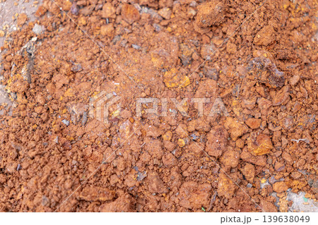 Close up view of red soil texture with granular clumps, representing natural land erosion, geological formation, or agricultural ground conditions for environmental and gardening projects Close up view of red soil texture with granular clumps, representing natural land erosion, geological formation, or agricultural ground conditions for environmental and gardening projects 139638049