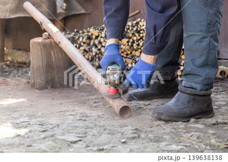 A professional construction worker uses a handheld electric angle grinder to smooth and polish a rusted metal pipe, showcasing industrial maintenance, manual labor, and expert metalwork skill A professional construction worker uses a handheld electric angle grinder to smooth and polish a rusted metal pipe, showcasing industrial maintenance, manual labor, and expert metalwork skill 139638138