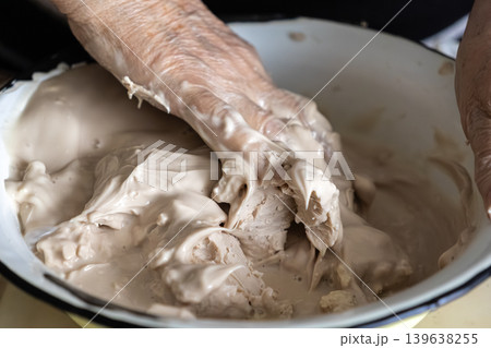 Elderly person mixing fresh yeast starter in a bowl, capturing the authentic process of traditional bread making and natural fermentation techniques for artisanal bakery production Elderly person mixing fresh yeast starter in a bowl, capturing the authentic process of traditional bread making and natural fermentation techniques for artisanal bakery production 139638255