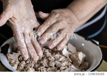Elderly person crumbling fresh yeast in a bowl for baking bread, emphasizing traditional culinary preparation methods and the craft of homemade artisan food production at home 139638260