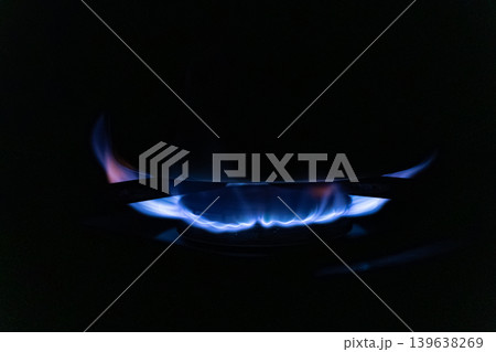 Blue gas flame burning on a kitchen stove burner in the dark, illustrating efficient energy consumption, modern cooking appliances, and domestic heat for preparing daily meals 139638269