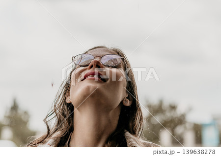 Woman rain glasses looking up at the sky during a rainstorm with copy space and cinematic mood Woman rain glasses looking up at the sky during a rainstorm with copy space and cinematic mood 139638278