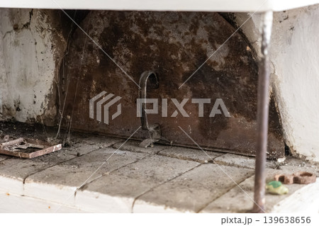 Old rusty metal oven door with handle in a vintage stone stove, capturing rustic atmosphere and history in a traditional cottage interior setting for heritage design projects 139638656