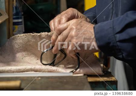 Skilled artisan hands carefully assembling eyewear frames on a workbench, showcasing traditional craftsmanship, precision, and quality maintenance in professional optical service 139638680