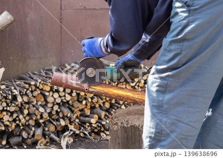 A dedicated worker uses an angle grinder to cut a metal pipe in a professional workshop with sparks flying to illustrate industrial repair, heavy maintenance, and fabrication tasks A dedicated worker uses an angle grinder to cut a metal pipe in a professional workshop with sparks flying to illustrate industrial repair, heavy maintenance, and fabrication tasks 139638696