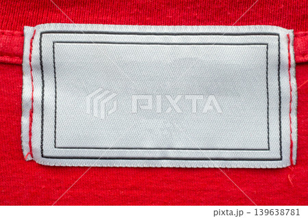 Blank white laundry care clothes label on red shirt fabric texture background Blank white laundry care clothes label on red shirt fabric texture background 139638781