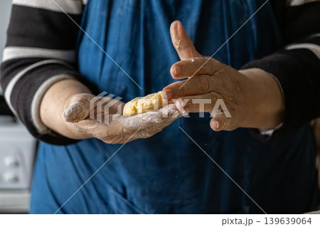 Woman hands forming cottage cheese pancake dough, preparing traditional syrniki for a homemade meal, emphasizing the craft of authentic culinary cooking and rustic kitchen lifestyle traditions 139639064