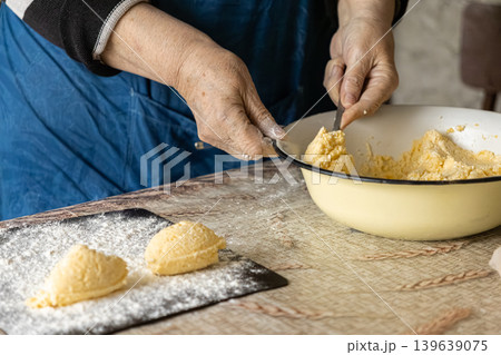 Elderly woman preparing traditional syrniki curd cheese pancakes in a home kitchen, highlighting artisan cooking, culinary heritage, manual food preparation and authentic rustic dining culture Elderly woman preparing traditional syrniki curd cheese pancakes in a home kitchen, highlighting artisan cooking, culinary heritage, manual food preparation and authentic rustic dining culture 139639075