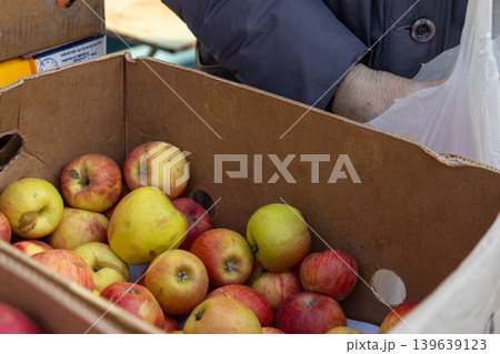 Fresh red and yellow apples sit in a cardboard box at a street market, symbolizing healthy local agricultural produce, the seasonal harvest, and a daily grocery lifestyle in the community 139639123