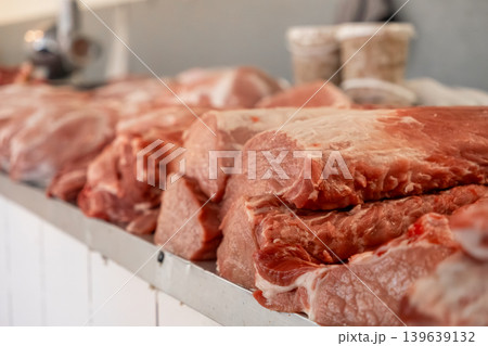 Fresh raw pork meat cuts displayed on a stainless steel counter in a butcher shop, representing high quality culinary supplies, traditional food processing and local farm to market trade Fresh raw pork meat cuts displayed on a stainless steel counter in a butcher shop, representing high quality culinary supplies, traditional food processing and local farm to market trade 139639132