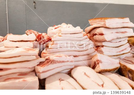 Fresh raw pork fat stacked on a butcher shop counter, showcasing high quality meat product for traditional cooking, culinary preparation, ingredient sourcing, and gastronomic market display 139639148