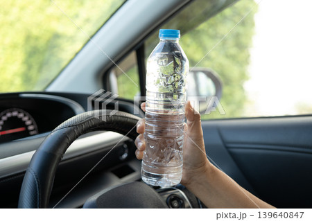 Asian woman driver holding bottle for drink water while driving a car. Plastic hot water bottle cause fire. Asian woman driver holding bottle for drink water while driving a car. Plastic hot water bottle cause fire. 139640847