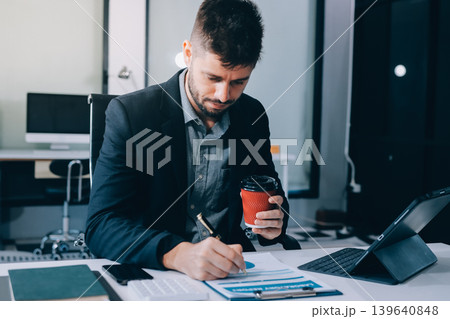 Tired worker. A tired businessman works in the evening. A man in office clothes is holding his temples. Problems in business. The businessman is trying to solve the problems that have arisen. Tired worker. A tired businessman works in the evening. A man in office clothes is holding his temples. Problems in business. The businessman is trying to solve the problems that have arisen. 139640848