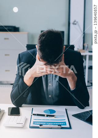 Tired worker. A tired businessman works in the evening. A man in office clothes is holding his temples. Problems in business. The businessman is trying to solve the problems that have arisen. Tired worker. A tired businessman works in the evening. A man in office clothes is holding his temples. Problems in business. The businessman is trying to solve the problems that have arisen. 139640857