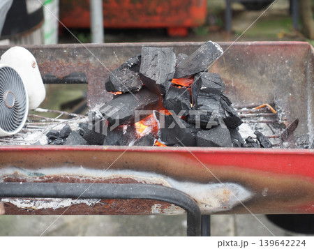 Charcoal fire ember heat grill smoke fuel glowing black coal burning metal brazier with orange flame and ash outdoor cooking 139642224
