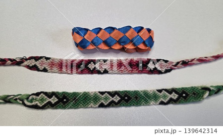 Set of three colorful handmade woven friendship bracelets made of threads and ribbons isolated on white background. Traditional diy textile craft hobby and summer youth accessories. Set of three colorful handmade woven friendship bracelets made of threads and ribbons isolated on white background. Traditional diy textile craft hobby and summer youth accessories. 139642314
