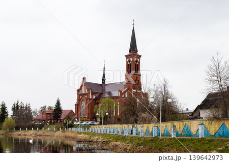 Scenic view of village church along river with autumn colors and reflective water Scenic view of village church along river with autumn colors and reflective water 139642973