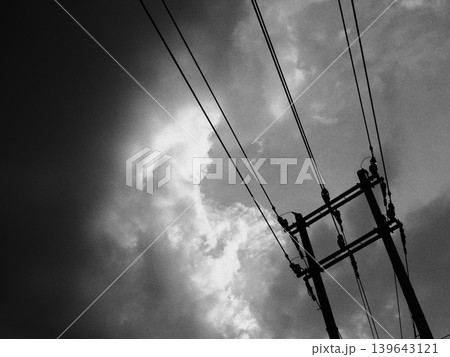 不穏な空に伸びる電線と電柱のモノクロ風景 139643121