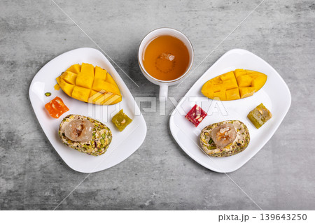 Cup of tea and plates with halva, mango fruit and sweets. 139643250