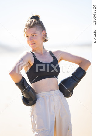 Determined woman posing with boxing gloves outdoor 139645324