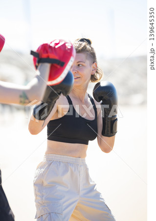 Woman training outdoor boxing hitting punching mitt 139645350