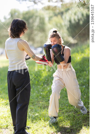 Women training boxing outdoors with punch mitts 139645587