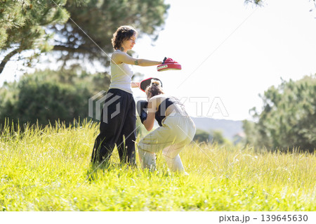 Two women training kickboxing with focus mitts outdoors Two women training kickboxing with focus mitts outdoors 139645630