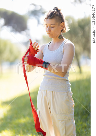 Woman wrapping hands preparing for combat sport training Woman wrapping hands preparing for combat sport training 139646177