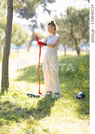 Woman preparing hand wraps for boxing training outdoors 139646214